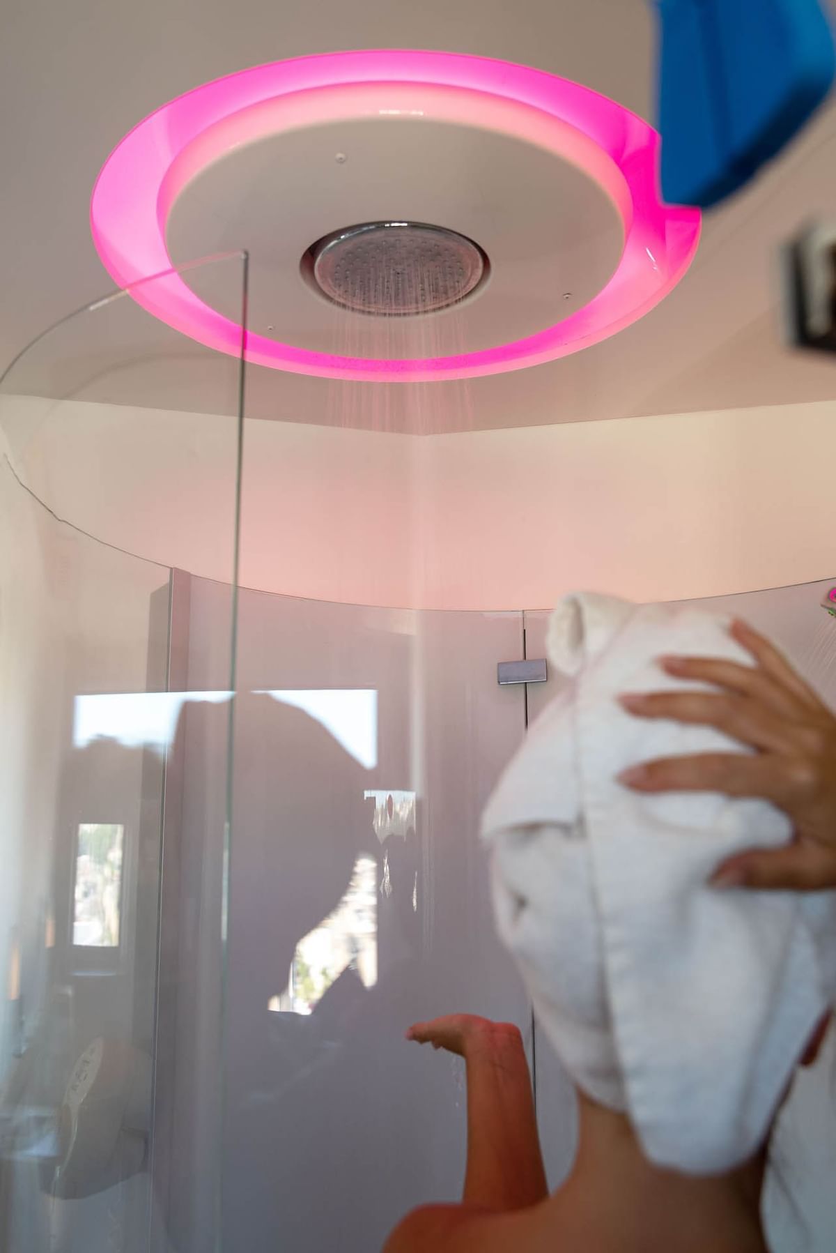 Une dame se baigne dans la zone de douche d'une salle de bain au Nomad Hotels