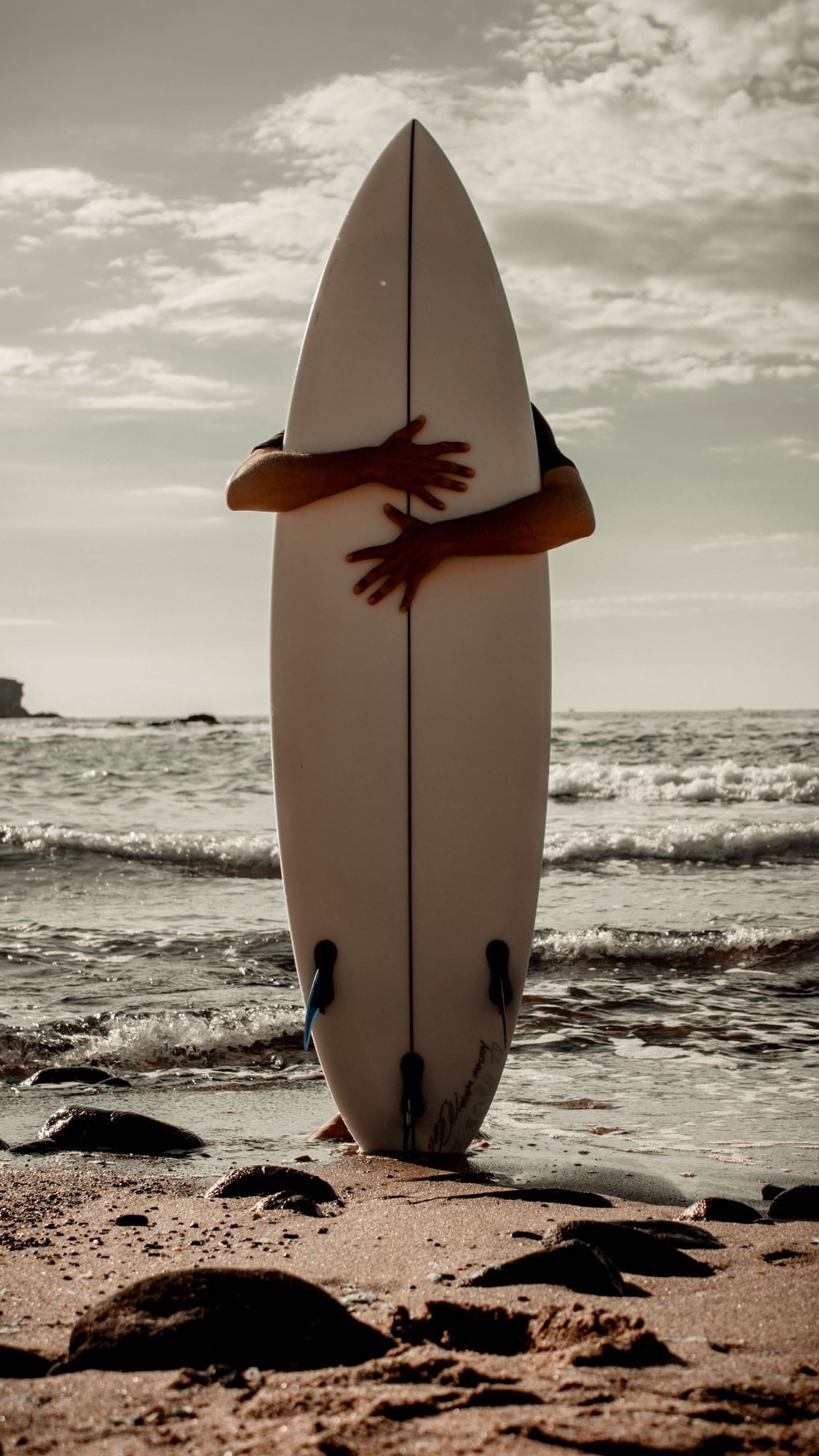 Homme debout derrière une planche de surf sur la plage, Oceania Hotels